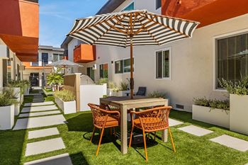 a backyard patio with a table and chairs under an umbrella at Kling Trio Apartments, Valley Village, CA, 91607